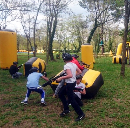 Cinq jeunes personnes se cachent et se protègent derrière un des obstacles gonflables du terrain de laser game